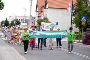 Seniorzy oraz władze miasta idący w przemarszu ulicami miasta