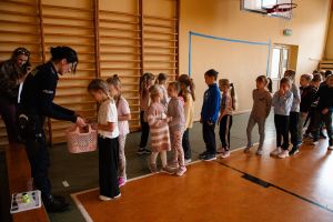 Dzieci odbierające prezenty od funkcjonariuszki policji