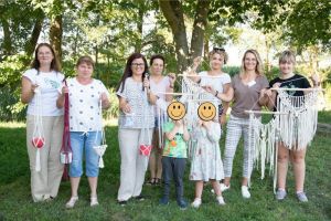 Zbiorowe zdjęcie uczestników warsztatu makramy wraz z wykonanymi przez nich dziełami